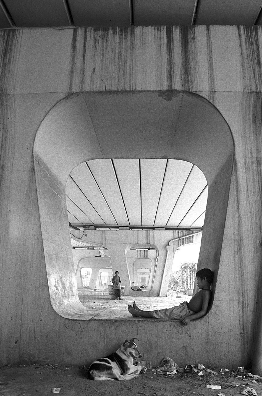 UNDER THE BRIDGE: A tired boy nestles in the niche of a concrete pillar supporting one of Delhi's busiest traffic crossings